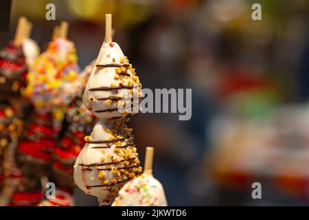 Erdbeere bedeckt mit weißer Schokolade und bedeckt mit Nüssen auf Spießen auf dem Boqueria Markt in Barcelona (Spanien). Stockfoto