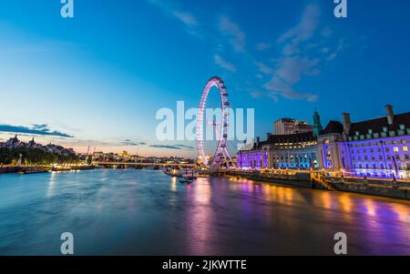 Wunderschöne Töne aus den Lichtern des London Aquarium und des London Eye spiegeln sich in der Dämmerung im Juli 2022 auf der Themse in London wider. Stockfoto