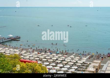 Sonnenschirme und Liegestühle mit Spazierwegen und Blumentöpfen mit Pflanzen am Strand Stockfoto