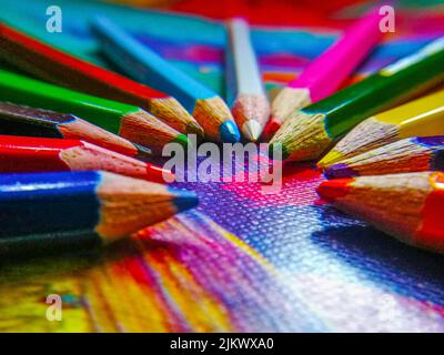 Stock Foto von Farbstift Buntstifte rund angeordnet und zeigt in der Mitte auf bunten Hintergrund. Bild aufgenommen in Bangalore, Karnataka, Indien. Stockfoto