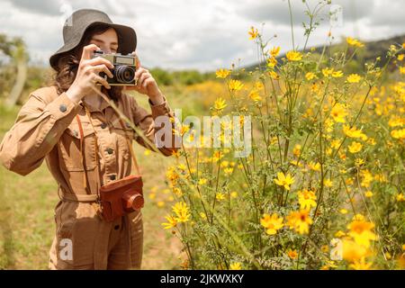 Weibliche Touristen fotografieren schöne Blumen im Afrika-Nationalpark Stockfoto