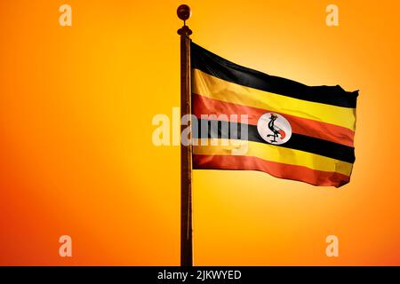 Eine Darstellung einer winkenden Flagge Ugandas aus dem Jahr 3D auf einem Pfosten auf orangefarbenem Hintergrund Stockfoto