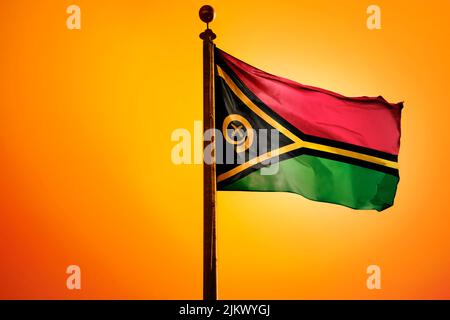 Die Nationalflagge von Vanuatu auf einem Fahnenmast isoliert auf einem orangen Hintergrund Stockfoto