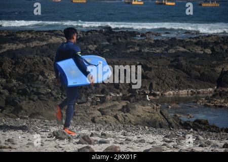 Ein junger Mann, der mit seinem Bodyboard am Strand in Iquique, Chile, läuft Stockfoto