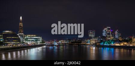 Ein Panorama der Skyline von London und des nächtlichen Wassers, aufgenommen von der Tower Bridge im August 2022. Besondere Sehenswürdigkeiten sind die C Stockfoto