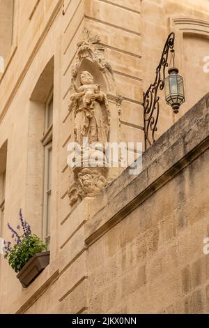 Avignon, eine Statue der Jungfrau Maria an der Fassade eines Hauses in einer typischen Straße, mit bunten Gebäuden Stockfoto