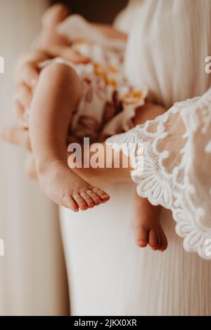 Eine vertikale Aufnahme der Füße eines Neugeborenen in den Händen einer Mutter Stockfoto