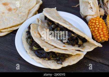 Teller mit mexikanischen Tacos gefüllt mit Huitlacoche auf rustikalem Holz Stockfoto