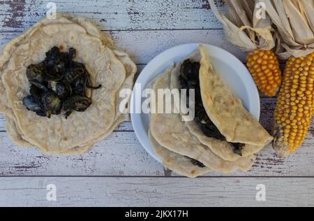 Teller mit mexikanischen Tacos gefüllt mit Huitlacoche auf rustikalem Holz Stockfoto