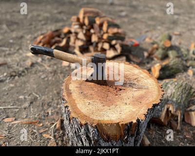 Eine alte Axt mit einem Holzgriff, die in einem Holzbalken steckt Stockfoto