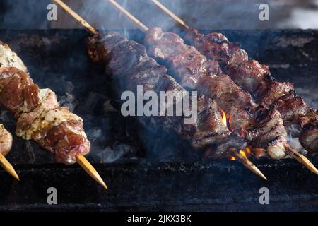 Marinierter Schaschlik, der auf einem Barbecue-Grill über Holzkohle zubereitet wird. Schaschlik oder Schisch Kebab beliebt in Russland. Braten von Rindfleisch-Kebabs auf dem BBQ Grill. Appetitlich, Stockfoto