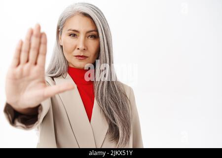 Nahaufnahme Porträt von Senior Asian Businesswoman, japanische Corporate Lady zeigt Stopp, verbieten, Ablehnung Geste, sagen nein mit ernstem Gesicht, weiß Stockfoto