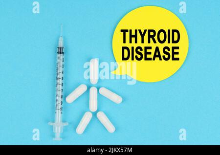 Medizin und Gesundheitskonzept. Spritze, menschliche Figur aus Pillen und Papieraufkleber mit der Aufschrift - SCHILDDRÜSENERKRANKUNG Stockfoto