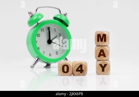Geschäfts- und Urlaubskonzept. Auf weißem Hintergrund gibt es einen Wecker und einen Kalender mit der Aufschrift - MAI 04 Stockfoto