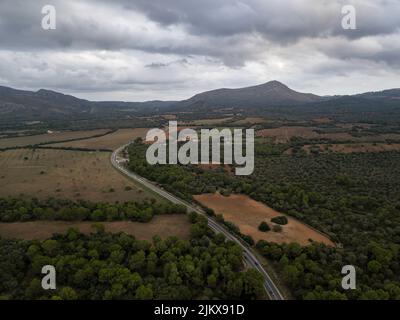 Luftaufnahme über kurvige Straße mit kleinem Verkehr auf der Insel Mallorca in Spanien. Keine Verkehrsstraße auf Mallorca in Spanien. Stockfoto