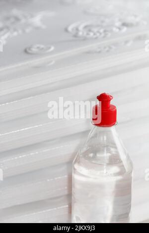 Flasche mit Acryl, vielseitiger, transparenter Klebstoff für Reparaturarbeiten, steht vor dem Hintergrund von gepressten Schaumplatten für die Decke Stockfoto