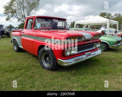 Chascomus, Argentinien - 09. Apr 2022: Alter roter Chevrolet Chevy C10 Apache Pickup Truck 1960-1961. Grünes Gras Natur Hintergrund. Dienstprogramm oder landwirtschaftliche Hilfsmittel Stockfoto