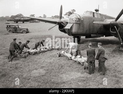 Waffenwagen mit 500 Pfund schweren GP-Bomben in Richtung der offenen Bombenbucht eines Armstrong Whitworth Whitley Mark V der Squadron RAF Nr. 58 in Linton-on-Ouse, Yorkshire, England. Der Armstrong Whitworth Whitley war ein britischer mittlerer Bomber, einer von drei zweimotorigen, Mittlere Bombertypen an der Front im Einsatz bei der Royal Air Force (RAF) bei Ausbruch des Zweiten Weltkriegs. Neben Vickers Wellington und Handley Page Hampden. 1942 wurde sie als Bomber von den größeren viermotorigen „Schweren“ wie der Avro Lancaster abgelöst. Stockfoto