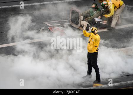 Philippinische See. 11.. Juli 2022. Aviation Boatswain's Mate (Handling) 3. Class Samuel Woodger aus London, England, steuert ein Flugzeug auf dem Flugdeck des einzigen vorwärts eingesetzten Flugzeugträgers der US-Marine USS Ronald Reagan (CVN 76). Ronald Reagan, das Flaggschiff der Carrier Strike Group 5, stellt eine kampfbereite Kraft zur Verfügung, die die Vereinigten Staaten schützt und verteidigt und Allianzen, Partnerschaften und kollektive maritime Interessen in der Indo-Pazifik-Region unterstützt. (USA Navy Foto von Mass Communication Specialist 2. Klasse Markus Castaneda) (Foto: © U.S. Navy/ZUMA Press Wire Ser Stockfoto