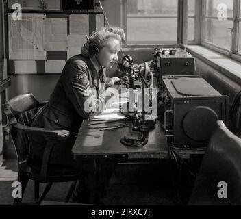 Ein WAAF-Funktelefonbetreiber, der vom Wachbüro einer Bomber Command Station aus mit dem Flugzeug kommuniziert. Die WAAF wurde 1939 gegründet, als die Regierung beschloss, dass ein separater Frauenflugdienst notwendig war. Die WAAF war weder eine unabhängige Organisation noch war sie vollständig in die RAF integriert. Vielmehr war sie mit der RAF verknüpft, so dass, wann immer möglich, das RAF-Personal durch Frauen ersetzt werden konnte. Stockfoto