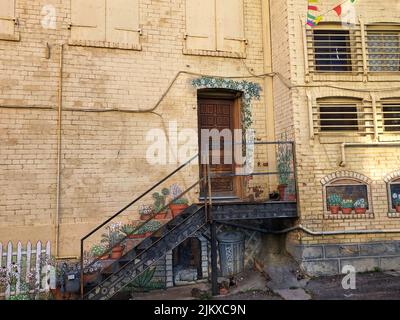 Eine schöne Aufnahme einer Metalltreppe, die an einem sonnigen Tag zu einer hölzernen Eingangstür zu einem alten Haus führt Stockfoto