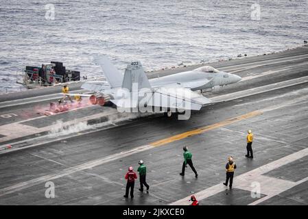 Philippinische See. 11.. Juli 2022. Eine F/A-18E Super Hornet, die an die 'Dambusters' von Strike Fighter Squadron (VFA) 195 befestigt ist, hebt auf dem Flugdeck des einzigen vorwärts eingesetzten Flugzeugträgers der US Navy USS Ronald Reagan (CVN 76) ab. Die Dambusters erhielten ihren Spitznamen am 1. Mai 1951, als die Skyraiders der Staffel den stark verteidigten und strategisch platzierten Hwacheon-Staudamm in Nordkorea mit Lufttorpedonen durch präzise Niederlagen zerstörten. Ronald Reagan, das Flaggschiff der Carrier Strike Group 5, stellt eine kampfbereite Truppe zur Verfügung, die die Vereinigten Staaten schützt und verteidigt Stockfoto