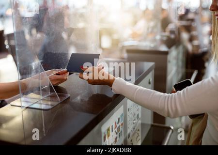 Eine weibliche Fluggast übergibt den Reisepass am Check-in-Schalter am Flughafen Stockfoto