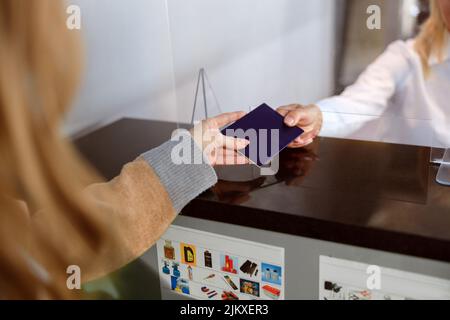 Frau, die ihren Pass bei der Passkontrolle am Flughafen aushändigte Stockfoto