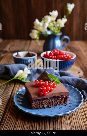 Süßes Kakaodessert mit Füllung aus roten Johannisbeeren, gekrönt mit Schokoladenmousse und frischen Beeren Stockfoto