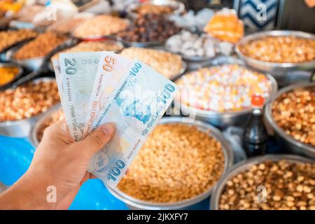 Türkische Lira-Geldscheine vor dem Hintergrund von Nüssen und getrockneten Früchten auf dem Bauernmarkt. Das Konzept der Konsumwirtschaft und des inflati Stockfoto