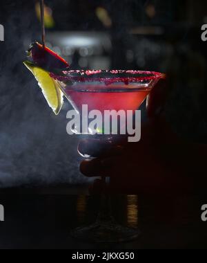 Eine vertikale Nahaufnahme eines Fruchtcocktails, isoliert auf dunklem Hintergrund. Erdbeere margarita. Stockfoto