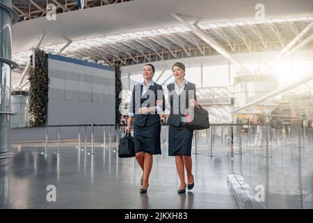 Zwei Flugbegleiter mit Taschen laufen durch das Terminal Stockfoto