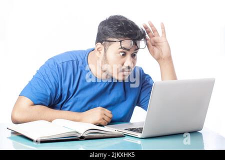 Schockierter Mann, der den Laptop-Bildschirm ansah, indem er die Brille ausnahm Stockfoto