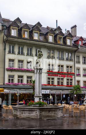 Eine vertikale Aufnahme des Brunnens gegen die historischen Gebäude in der Innenstadt von Bern, Schweiz. Stockfoto