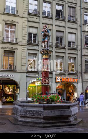 Eine vertikale Aufnahme des Brunnens gegen das historische Gebäude in der Innenstadt von Bern, Schweiz. Stockfoto