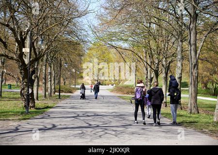 Eine Landschaft von Menschen, die an einem sonnigen Tag auf einem Wanderweg des Cytadela-Parks in Posen, Polen, spazieren gehen Stockfoto