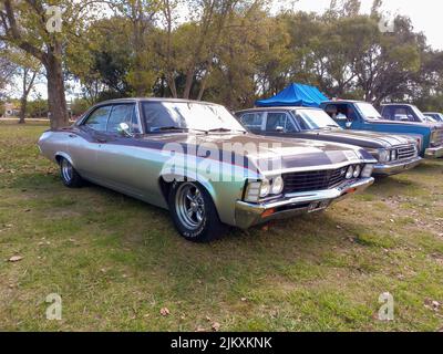 Avellaneda, Argentinien - Mar 20, 2022 - der alte beliebte Chevrolet Chevy Impala, viertürige Limousine Ende 1960s von GM, parkte auf dem Land. Natur Gras und Stockfoto