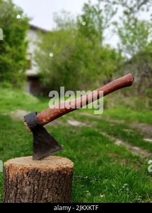 Stecken Axt in einem Log im Hinterhof einer Villa Stockfoto