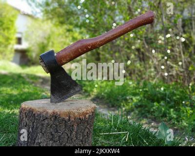 Stecken Axt in einem Log im Hinterhof einer Villa Stockfoto