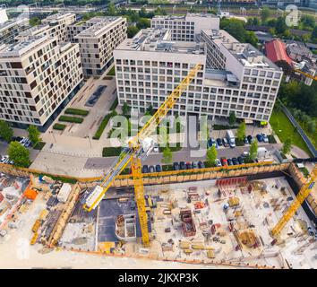Quadratische Drohnenperspektive der Baustelle im Zentrum von Warschau. Zwei gelbe Krane arbeiten an einem neuen Gebäude. Hochwertige Fotos Stockfoto