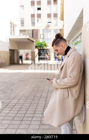 Junger Mann mit gemischter Rasse und Smartphone auf der Straße Stockfoto