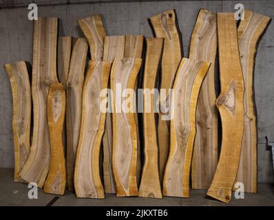 Eine Nahaufnahme von geschnittenen Holzplanken, die auf eine schmutzige, raue Wand eines Lagerhauses gelehnt sind Stockfoto