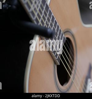 Nahaufnahme einer braunen klassischen Gitarre in hellem Licht mit verschwommenem Hintergrund Stockfoto