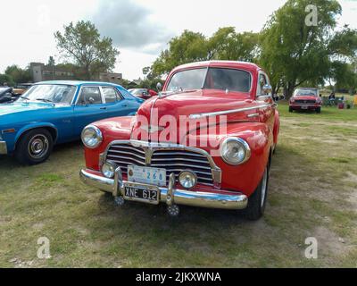 Chascomus, Argentinien - 9. Apr 2022: Der alte rote Chevrolet Chevy Stylesmaster 1948 Coupé von General Motors parkte auf dem Land. Naturrasen Stockfoto