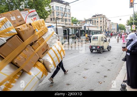 Ein Jugendlicher, der einen großen, von Hand gezogenen Wagen mit eingewickelten Schachteln schleppt. Fatih, Istanbul, Türkei Stockfoto