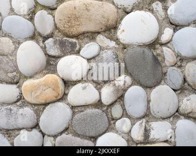 Wandfliesen aus großen glatten Steinen. Kieselsteine in Zement. Kreative Wanddekoration. Steine vom Strand Stockfoto