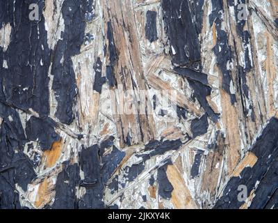 Spanplatte in schwarzer Farbe. Hintergrund von einem bemalten Brett. Muster. Holzhintergrund. Komprimierte Chips. Alte, schäbige Wand, blätternde Farbe Stockfoto