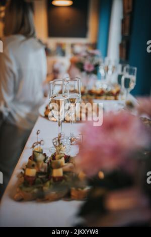 Eine Tischplatte voller Gläser Sekt mit Canapes und Antipasti im Hintergrund Stockfoto