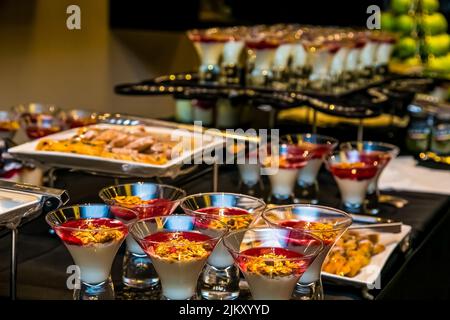 Eine Nahaufnahme von köstlichen Desserts in Glasbechern auf einem Metalltablett Stockfoto