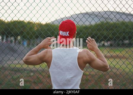 Eine Nahaufnahme von hinten eines Mannes, der ein Metallnetz in einer roten Kappe hält. Stockfoto
